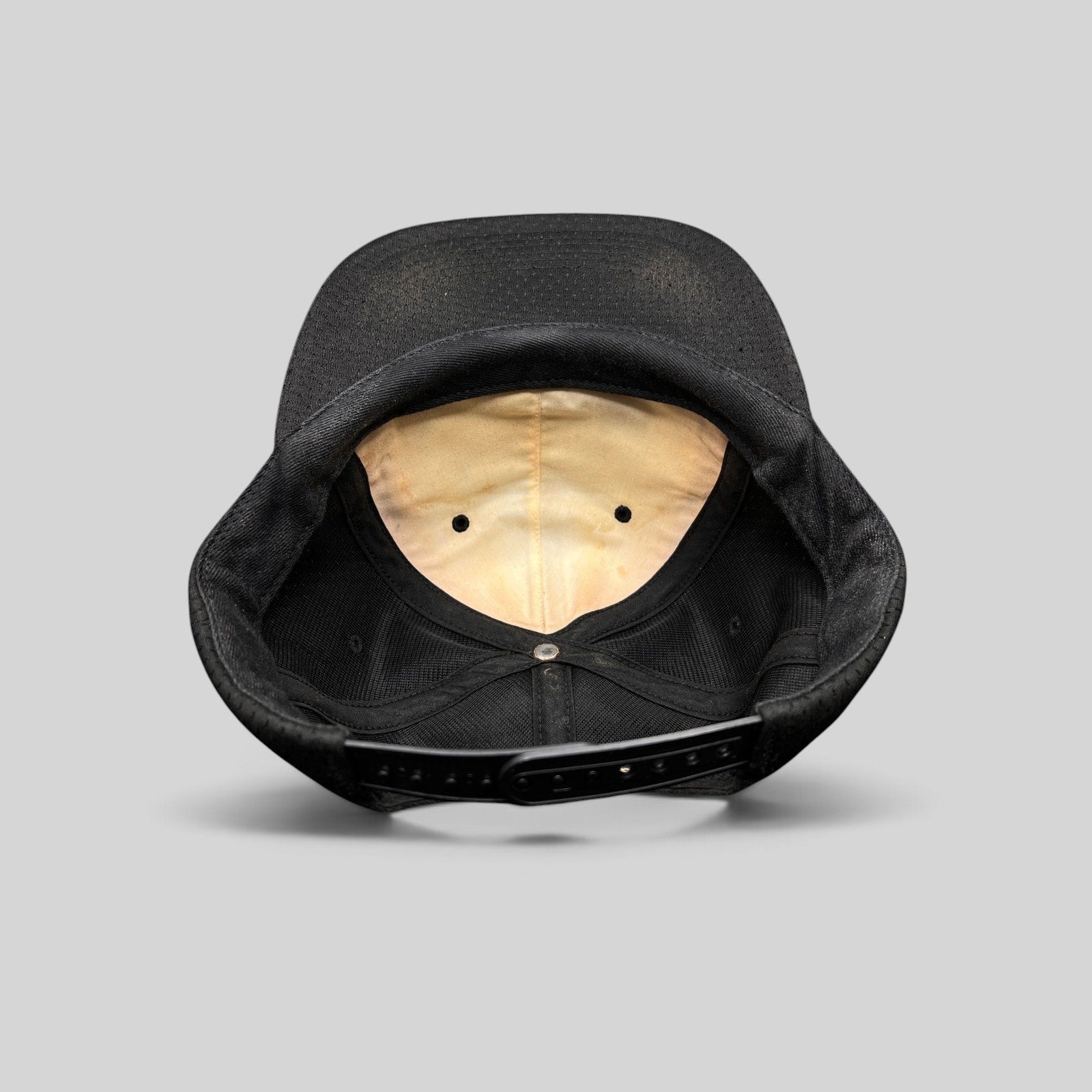 Raree Finds vintage black Supreme mesh snapback hat showing the interior lining and adjustable plastic strap