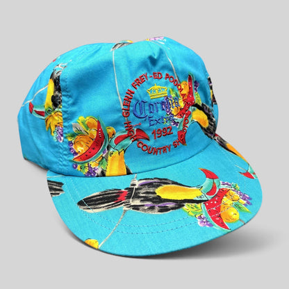Raree Finds vintage 1992 High Country Shootout golf hat in turquoise with tropical toucan print and strapback closure.