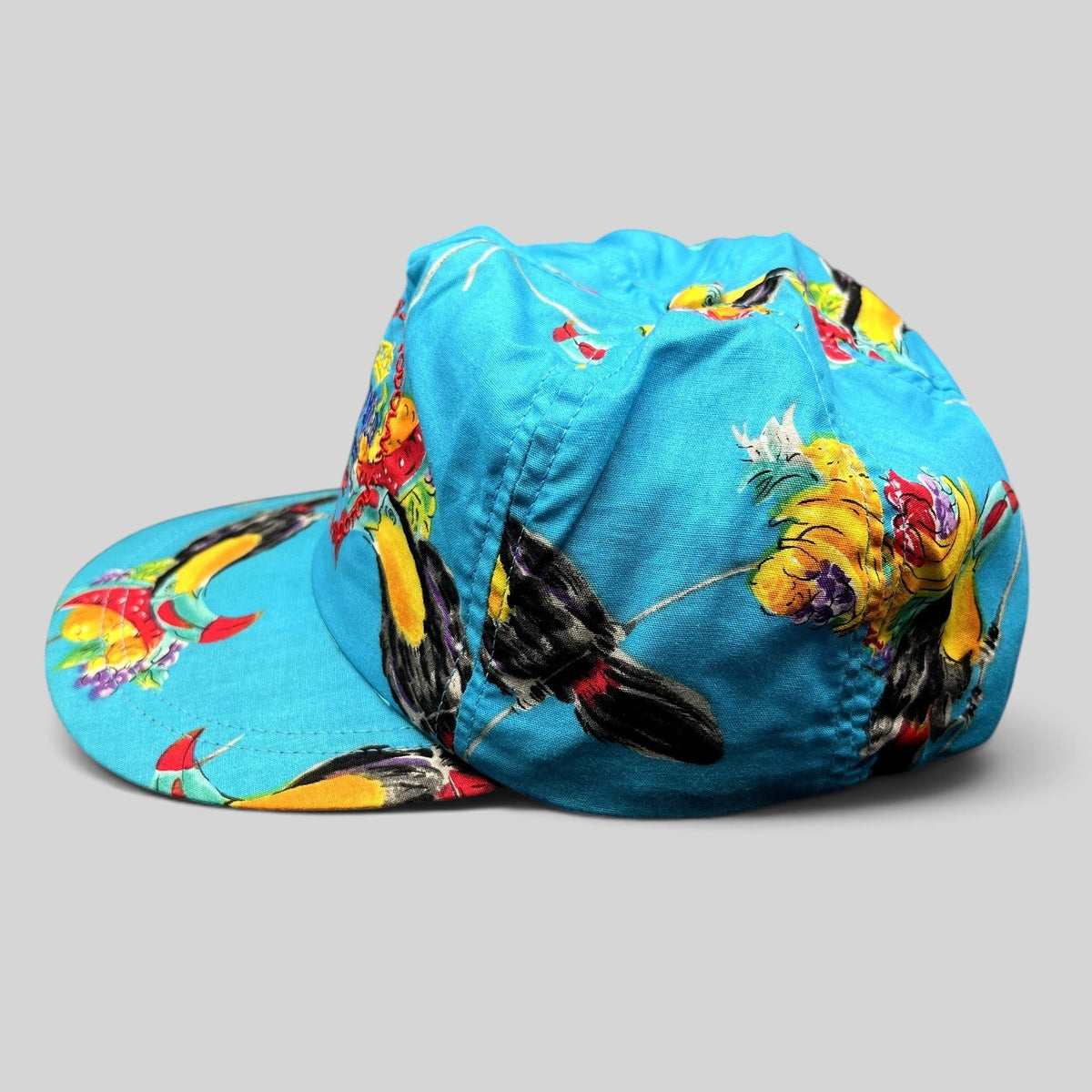 Raree Finds vintage 1992 High Country Shootout golf hat in turquoise with a tropical toucan and fruit print.