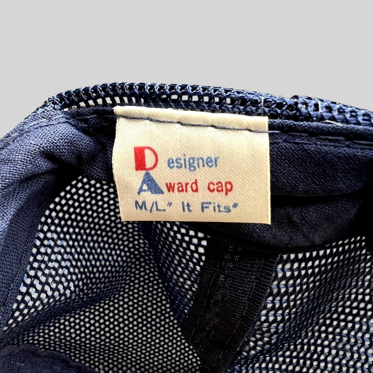 Raree Finds vintage Designer Award Cap label inside a navy mesh trucker hat with M/L sizing detail