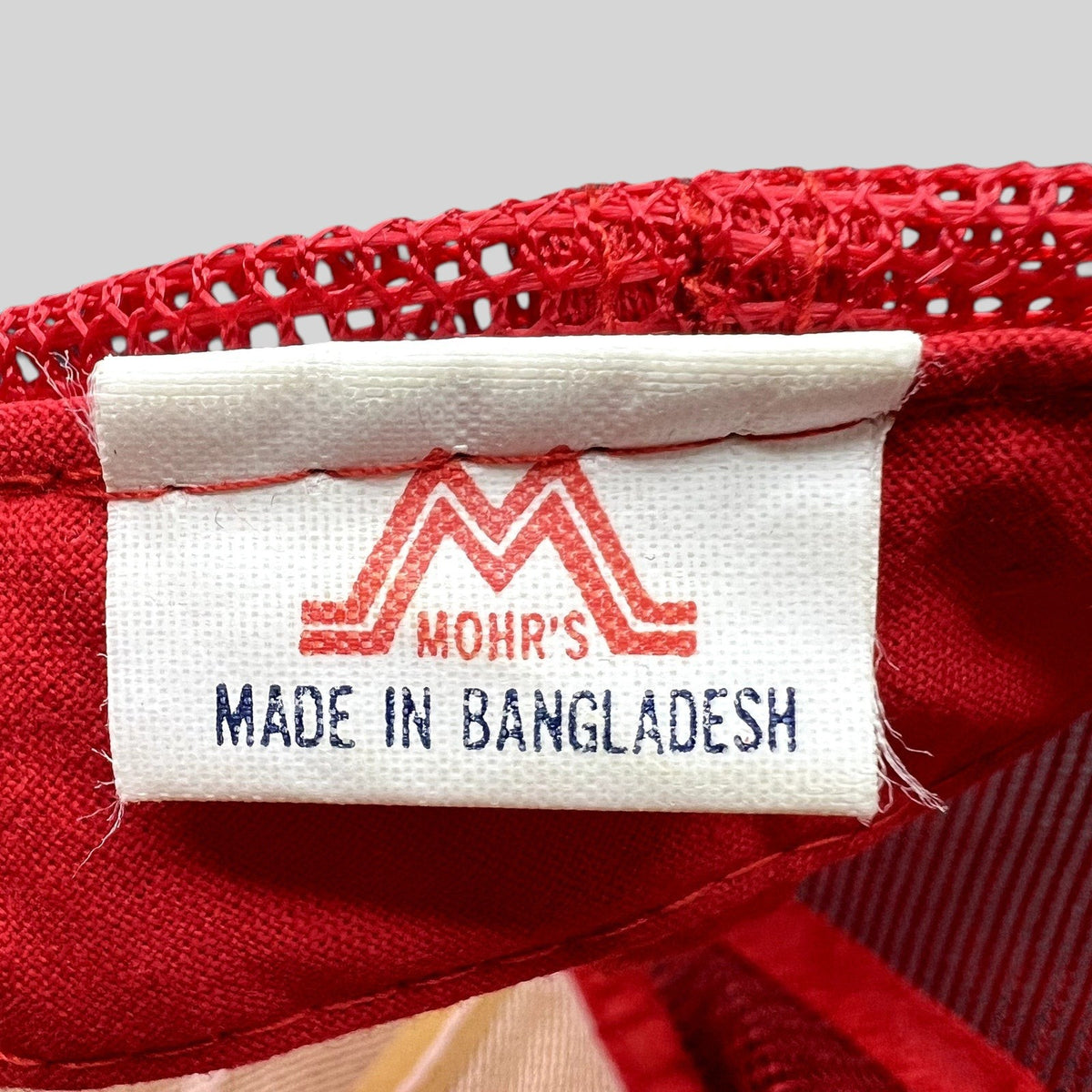 Raree Finds vintage trucker hat interior tag with Mohrs logo and Made in Bangladesh label on red mesh fabric