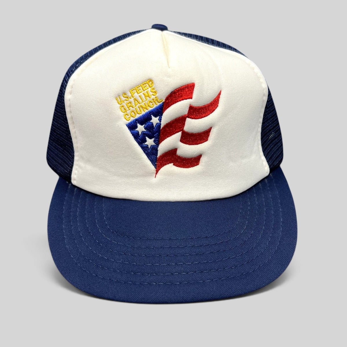 Raree Finds vintage U.S. Feed Grains Council trucker hat with white foam front, navy mesh back, and patriotic logo.