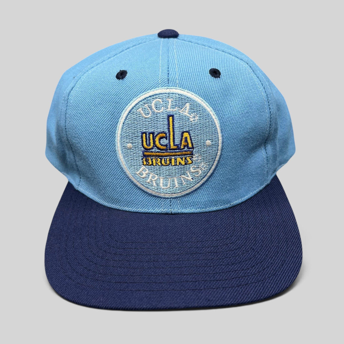 Raree Finds vintage AJD UCLA Bruins snapback hat with light blue crown, navy brim, and circular embroidered logo.
