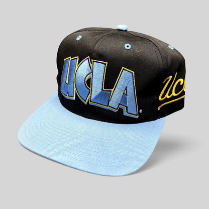 Raree Finds vintage 90s UCLA Bruins snapback hat with black crown, powder blue brim, and oversized script embroidery.