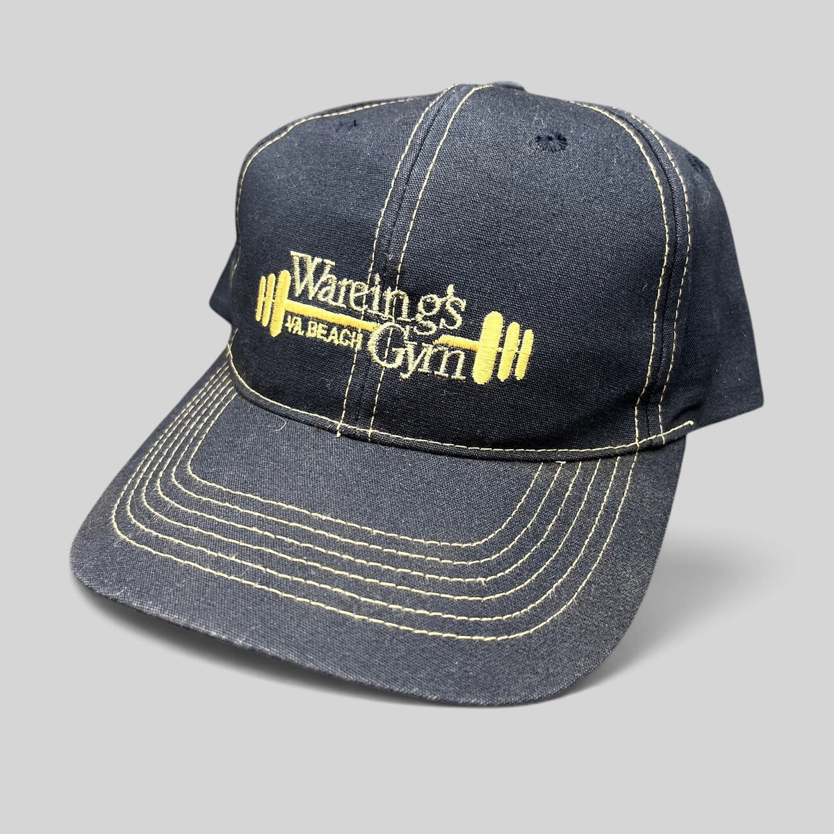 Raree Finds vintage navy blue Wareing’s Gym snapback hat with gold embroidered barbell logo and contrast stitching.