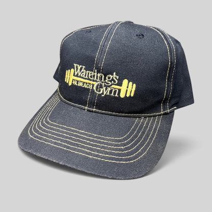 Raree Finds vintage navy blue Wareing’s Gym snapback hat with gold embroidered barbell logo and contrast stitching.
