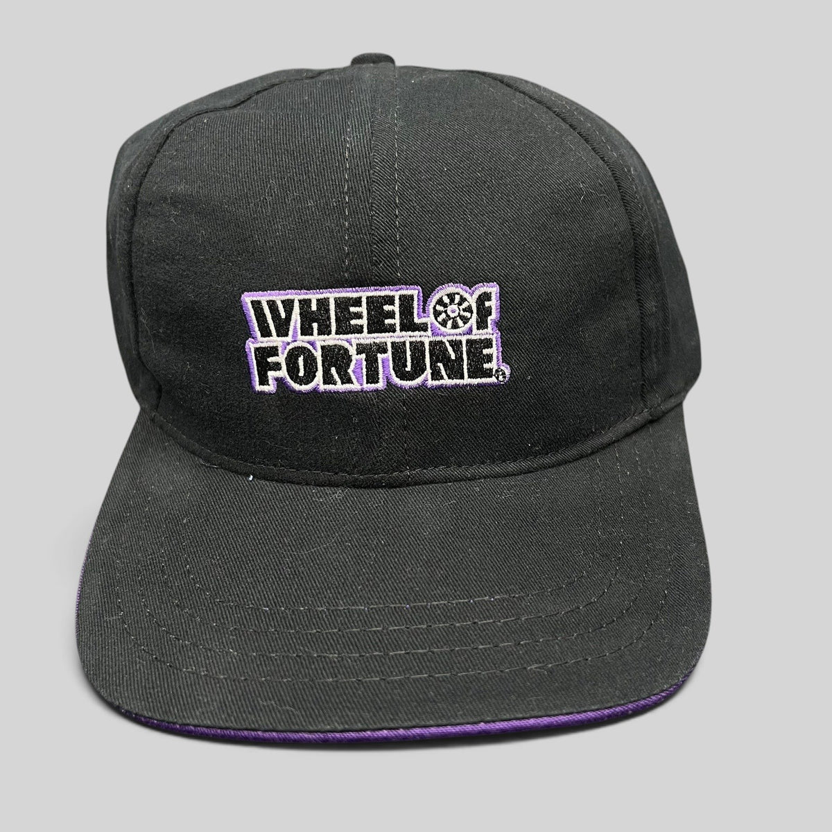 Raree Finds vintage black snapback hat with purple brim and embroidered Wheel of Fortune logo by Competition Headwear