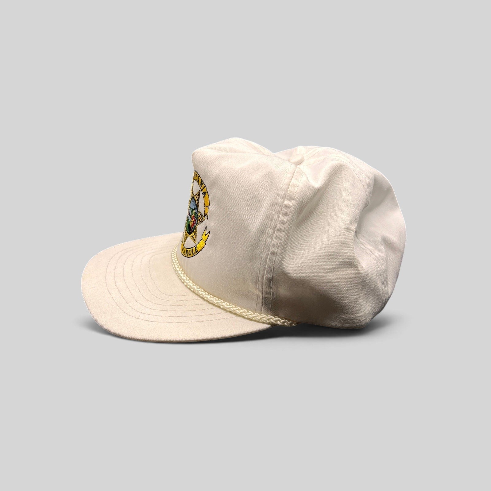 Raree Finds vintage 90s white Otto snapback hat with California State Parole emblem and braided rope on the brim.
