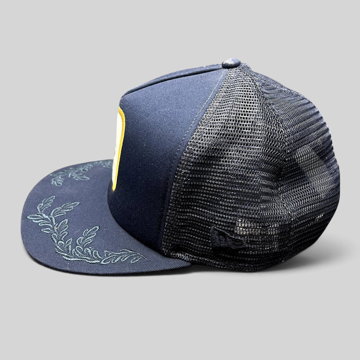 Raree Finds Volcom x New Era 9FIFTY navy trucker hat with embroidered leaf brim detail and mesh back panels.