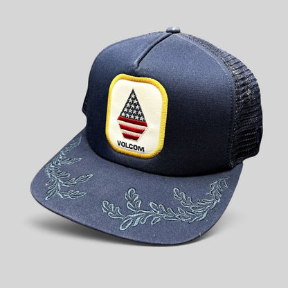 Raree Finds Volcom x New Era 9FIFTY navy trucker hat with USA flag stone logo patch and embroidered brim detailing