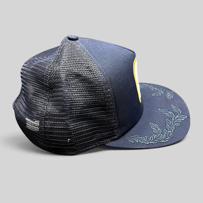 Raree Finds Volcom x New Era 9FIFTY navy trucker hat with mesh back, flat brim, and tonal leaf embroidery.