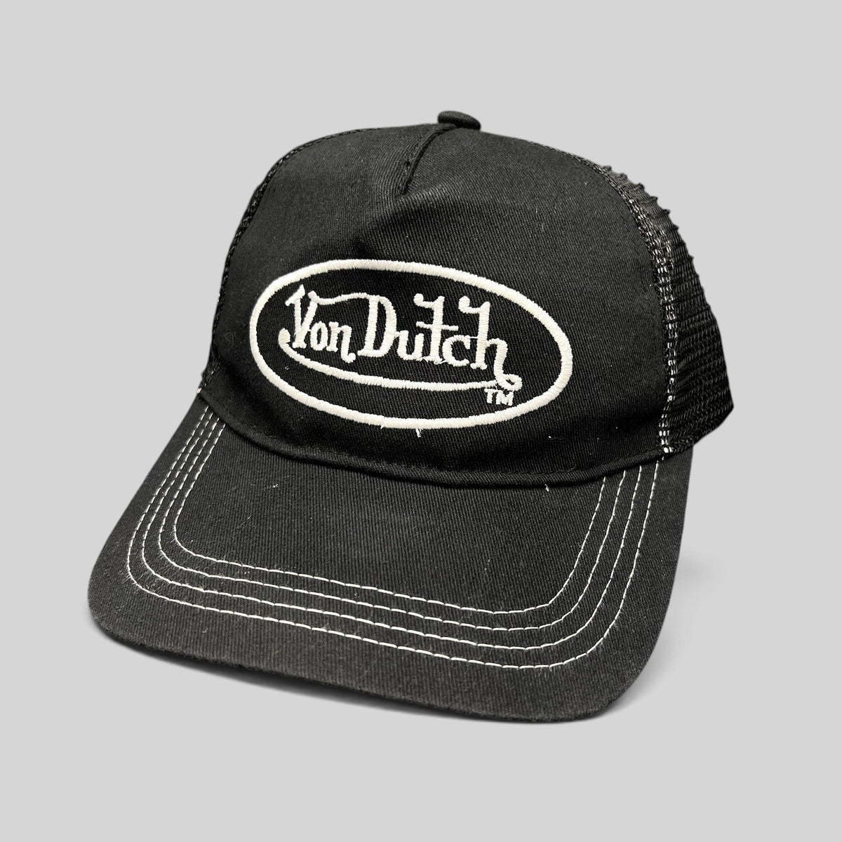 Raree Finds vintage Von Dutch black trucker hat with white oval logo embroidery, mesh back, and contrast stitching.
