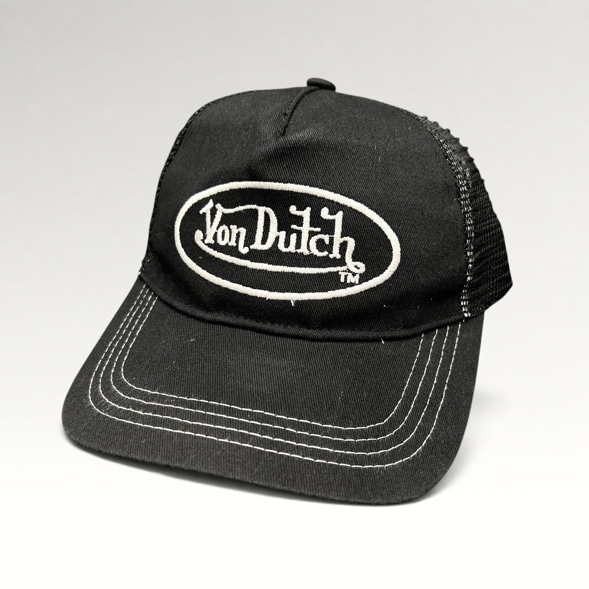 Raree Finds vintage Von Dutch black trucker hat with white oval logo embroidery, mesh back, and contrast stitching.