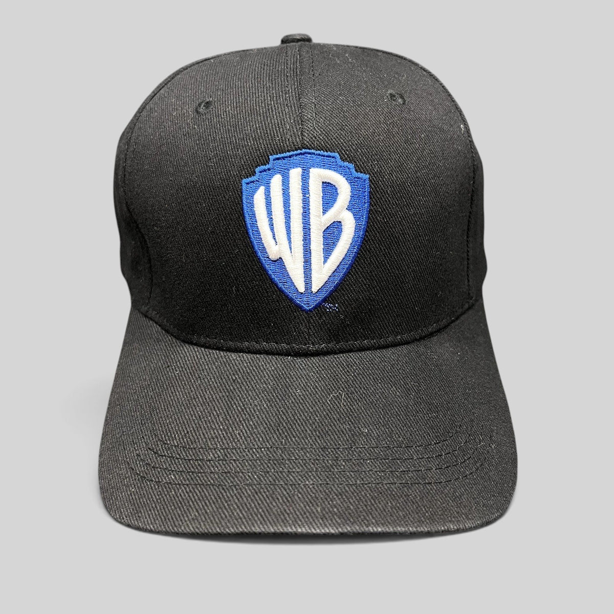 Raree Finds black fitted hat featuring an embroidered blue and silver Warner Bros WB shield logo on the front crown.