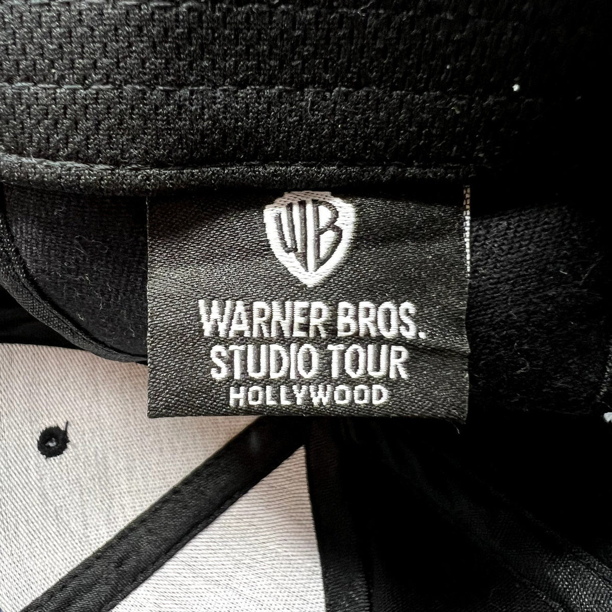 Raree Finds Warner Bros Studio Tour Hollywood hat interior label with WB shield logo on black fabric