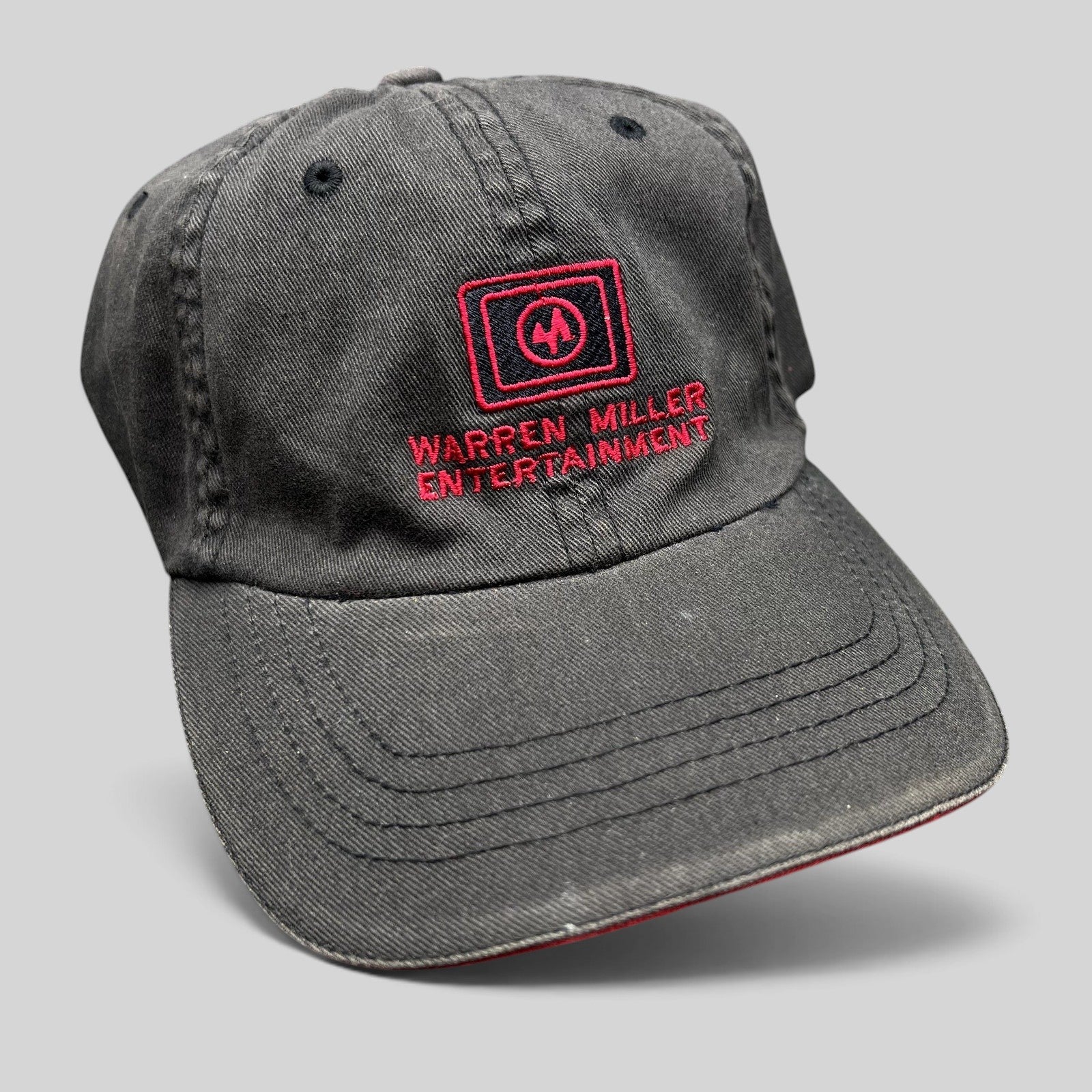 Raree Finds vintage black Flexfit hat with red Warren Miller Entertainment logo embroidery and contrast brim piping.
