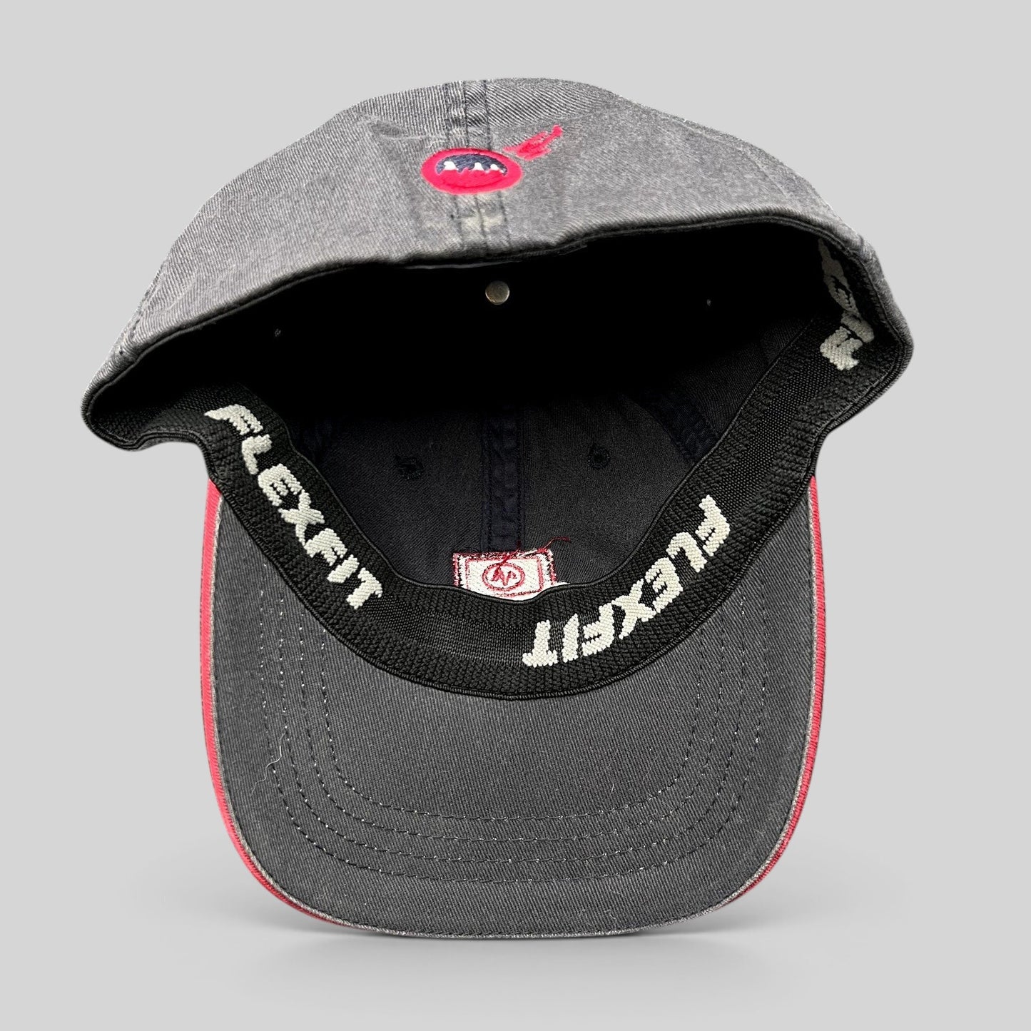 Raree Finds vintage Warren Miller Entertainment Flexfit hat showing the interior black sweatband and red brim piping