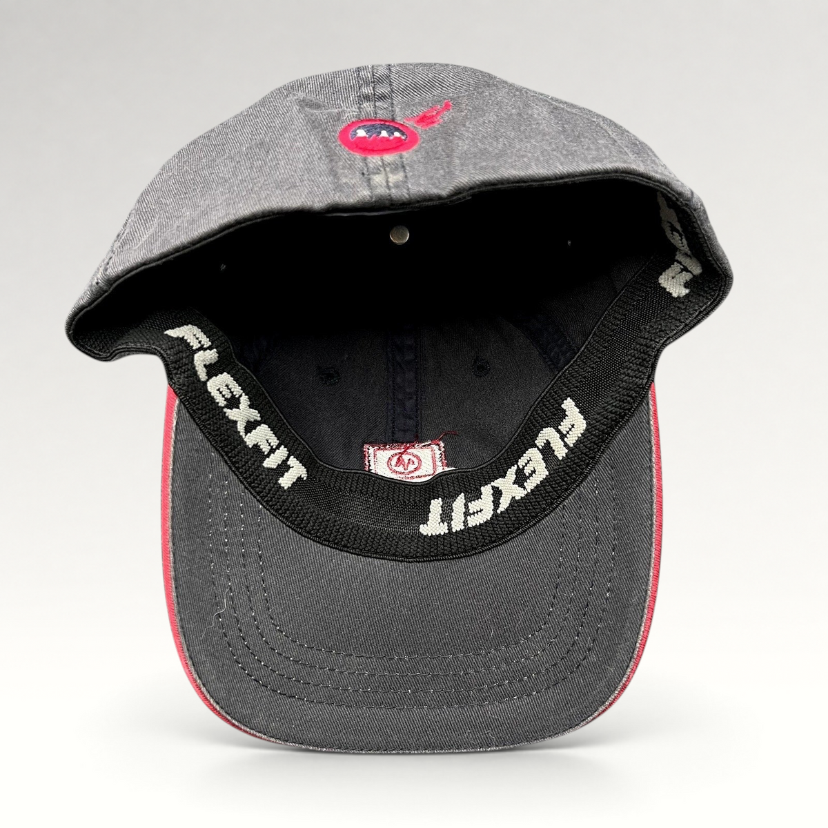 Raree Finds vintage Warren Miller Entertainment Flexfit hat showing the interior black sweatband and red brim piping
