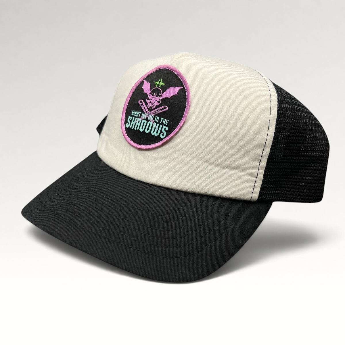 Raree Finds What We Do in the Shadows trucker hat with cream foam front, black mesh back, and gothic skull patch.
