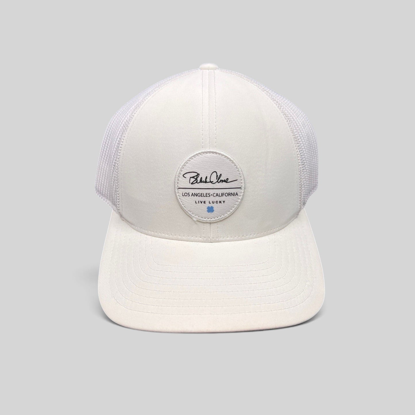 Raree Finds white Black Clover trucker hat with Live Lucky patch and blue clover detail on a structured mesh back