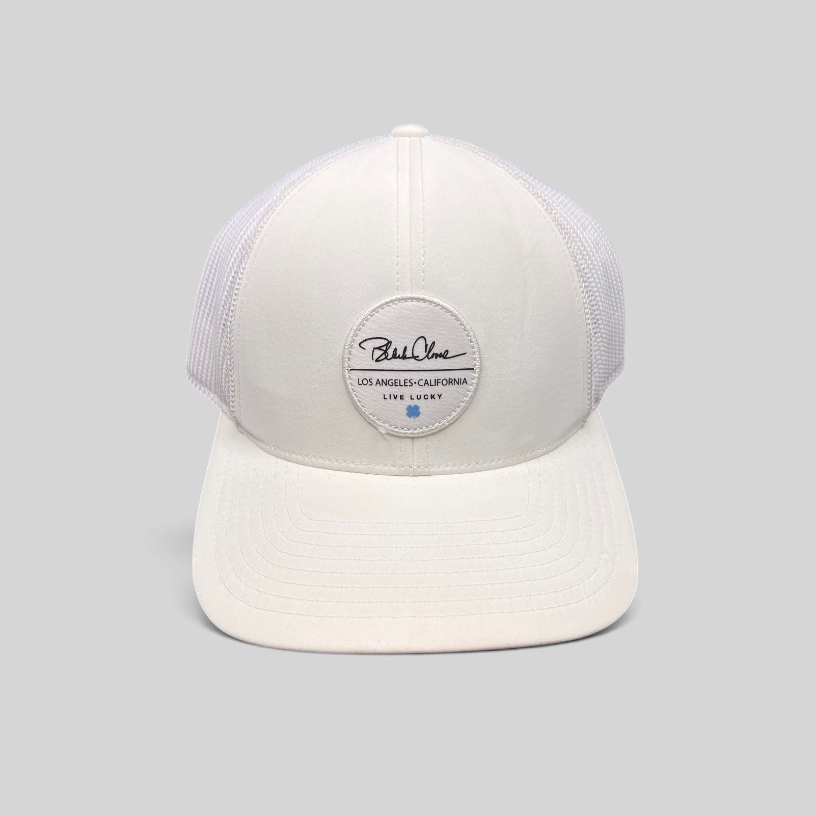 Raree Finds white Black Clover trucker hat with Live Lucky patch and blue clover detail on a structured mesh back