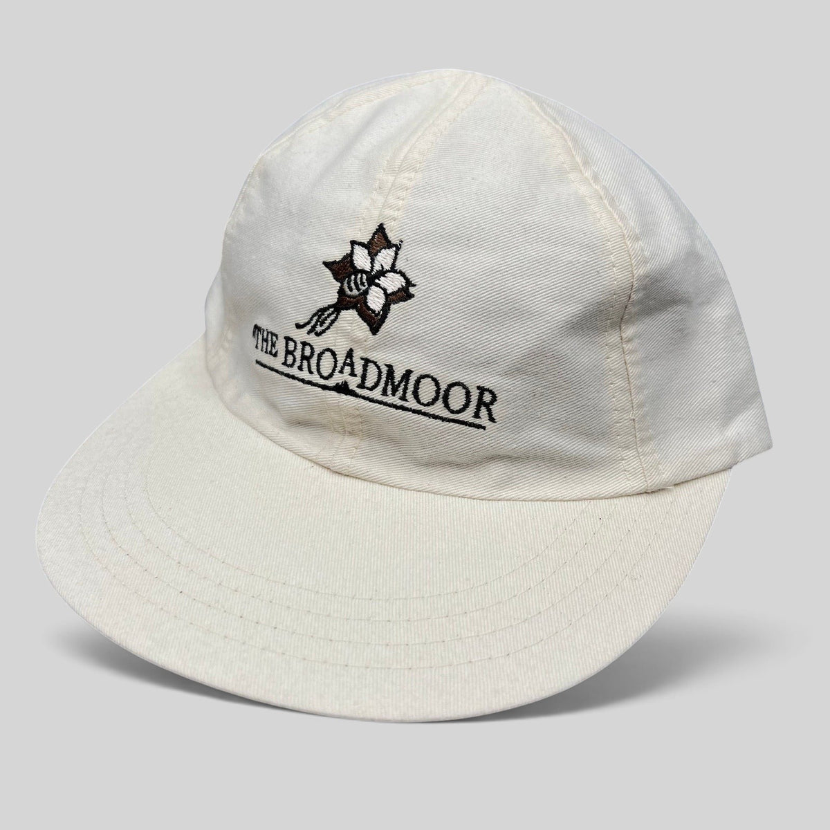Raree Finds white cotton strapback golf hat featuring The Broadmoor floral logo and script embroidery