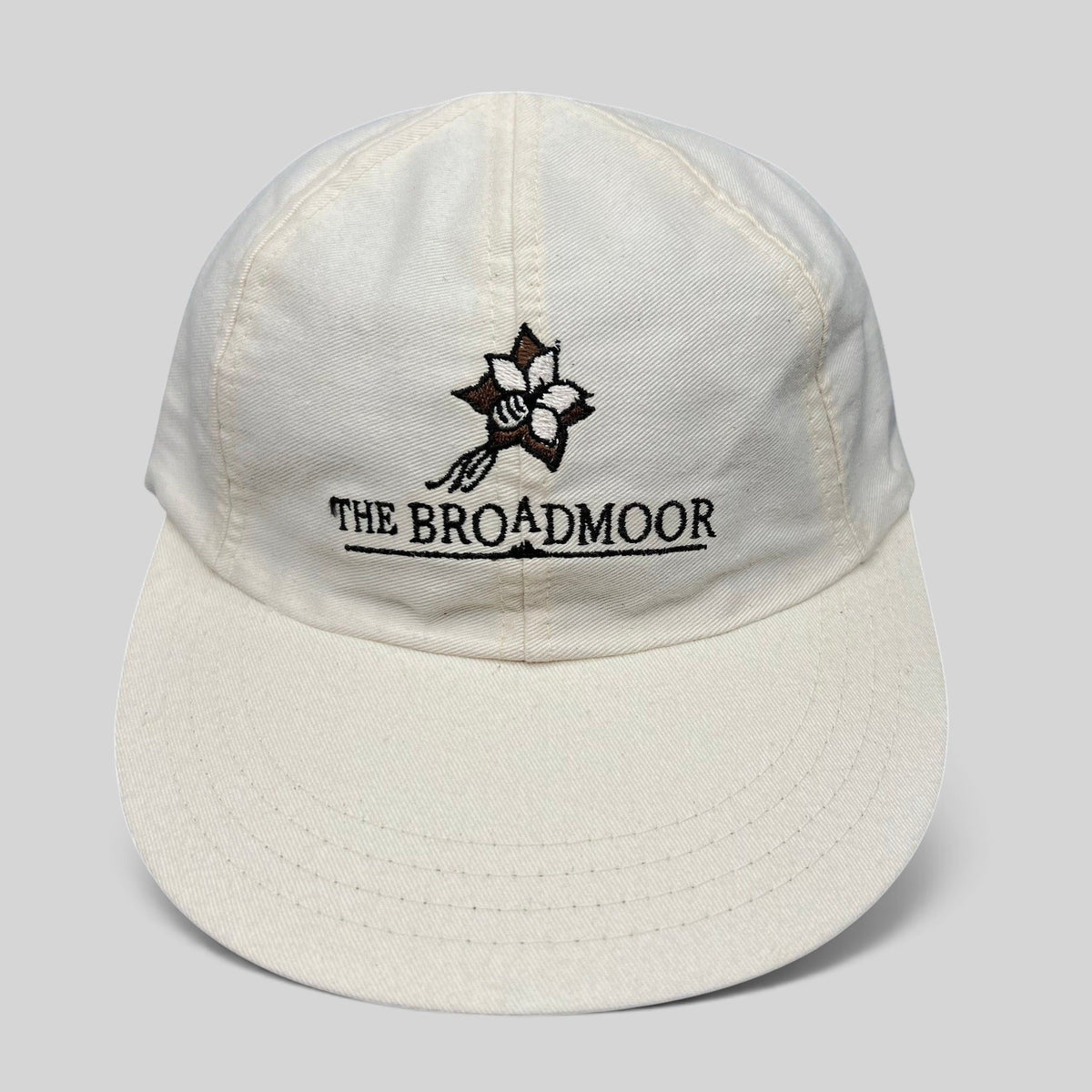 Raree Finds white cotton strapback golf hat featuring The Broadmoor floral logo and script embroidery