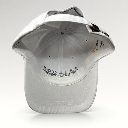 Raree Finds white cotton strapback cap with brass buckle and interior Trilogy branding, viewed from the back.