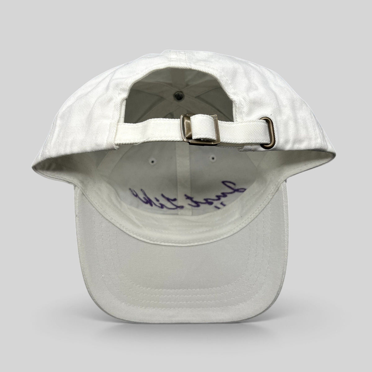 Raree Finds white cotton dad cap with adjustable brass buckle strapback and purple script embroidery on the interior