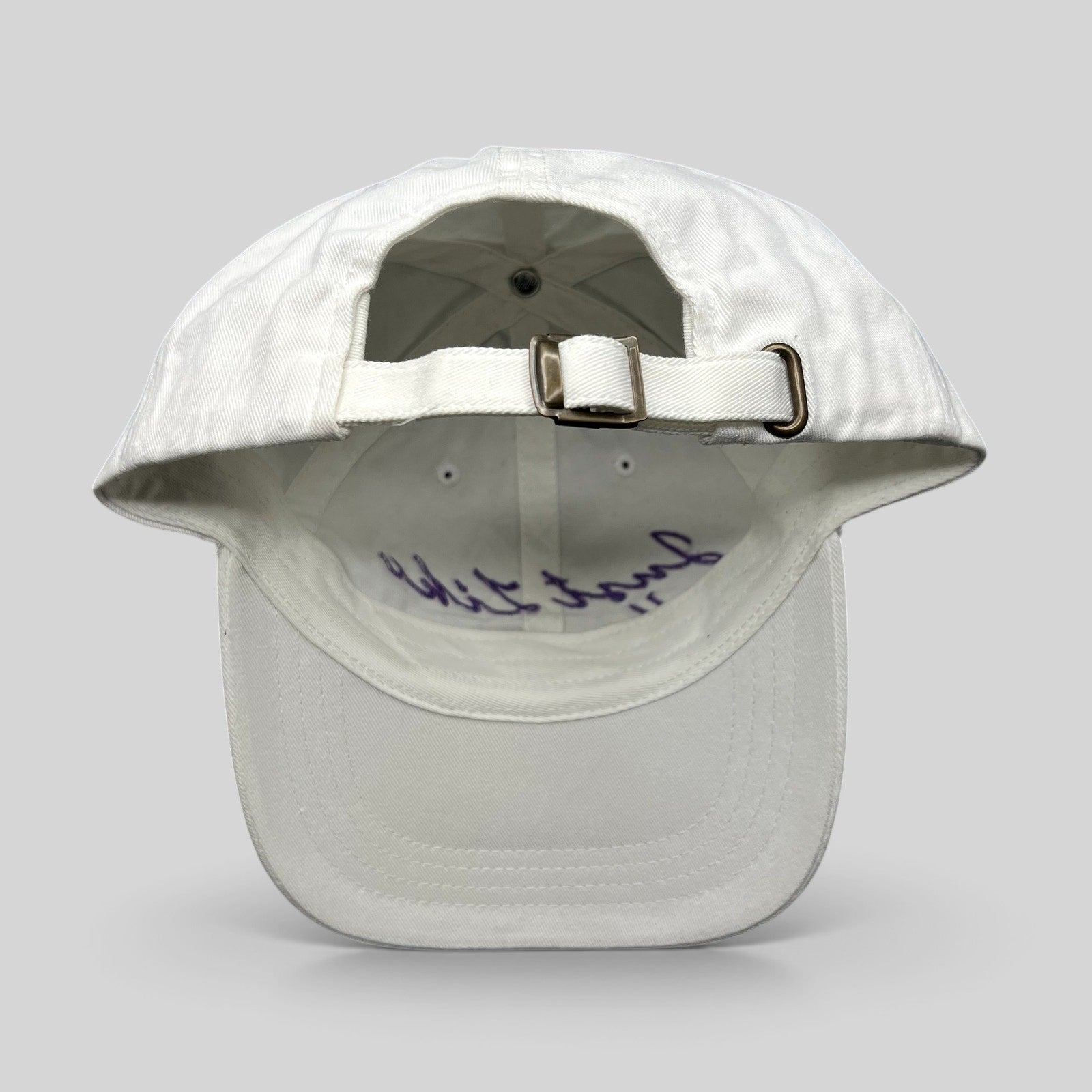 Raree Finds white cotton dad cap with adjustable brass buckle strapback and purple script embroidery on the interior