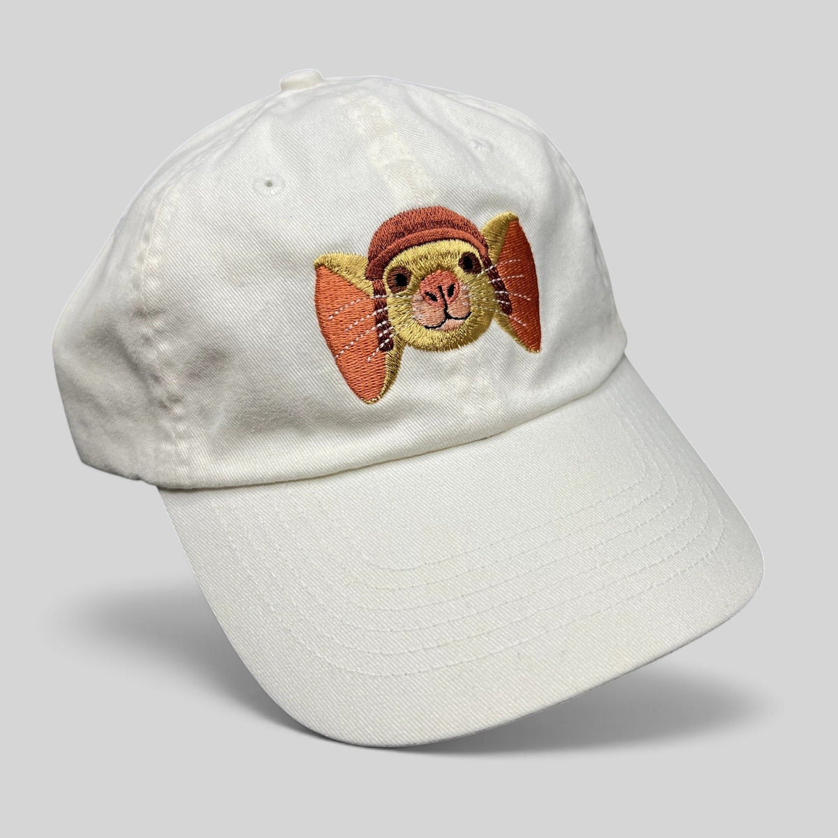 Raree Finds white cotton strapback hat featuring an embroidered Tale of Despereaux mouse character for youth.