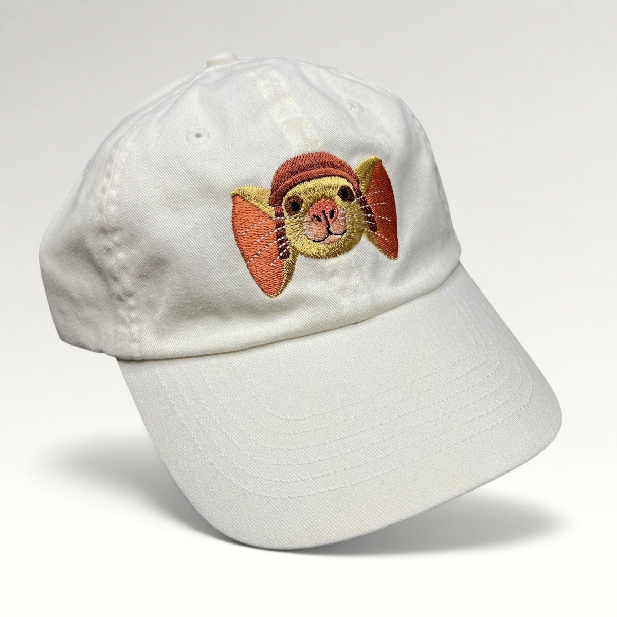 Raree Finds white cotton strapback hat featuring an embroidered Tale of Despereaux mouse character for youth.