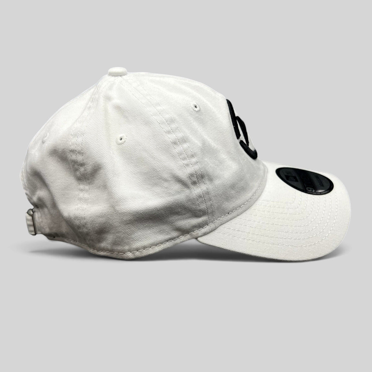 Raree Finds white New Era 9TWENTY dad hat with black embroidered music logo and curved brim, side profile view.