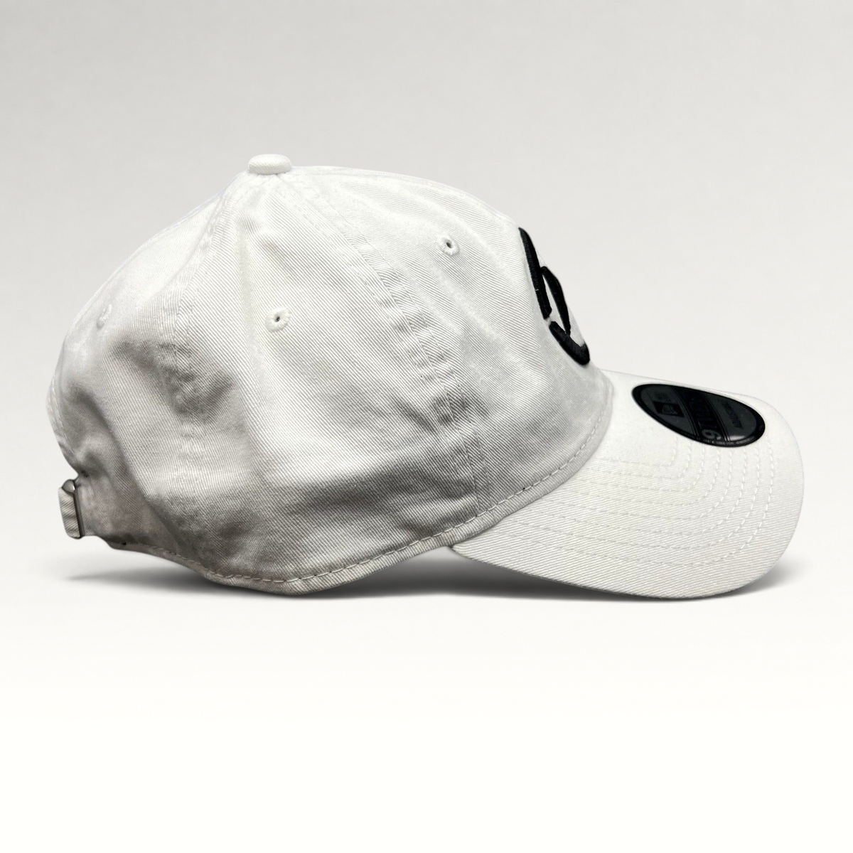 Raree Finds white New Era 9TWENTY dad hat with black embroidered music logo and curved brim, side profile view.