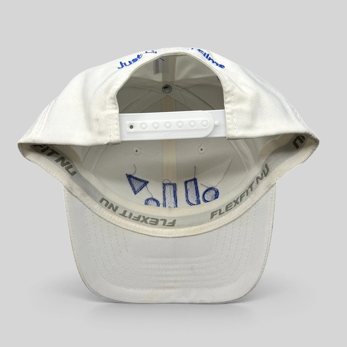 Raree Finds white Flexfit NU snapback hat showing interior royal blue embroidery and adjustable plastic strap