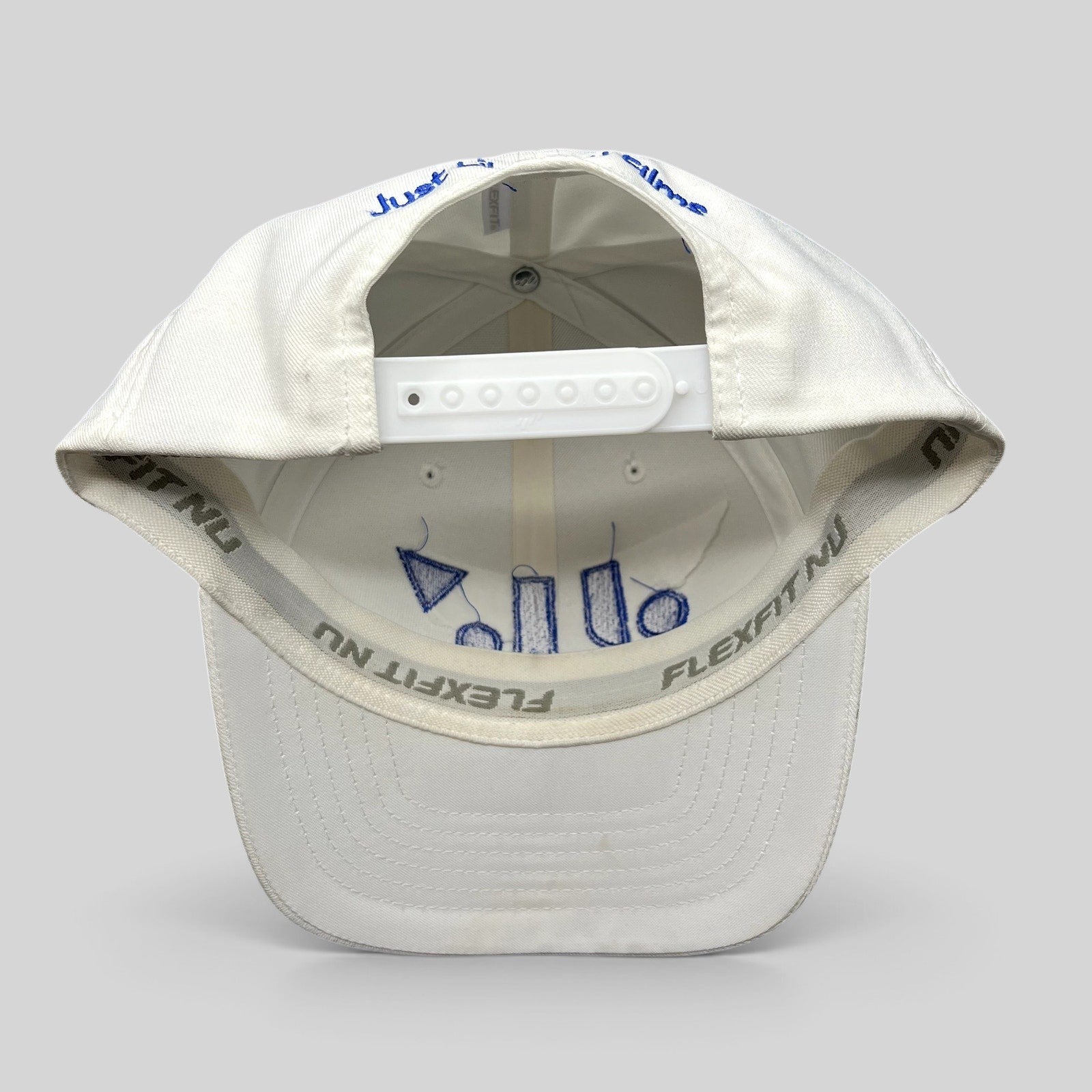 Raree Finds white Flexfit NU snapback hat showing interior royal blue embroidery and adjustable plastic strap