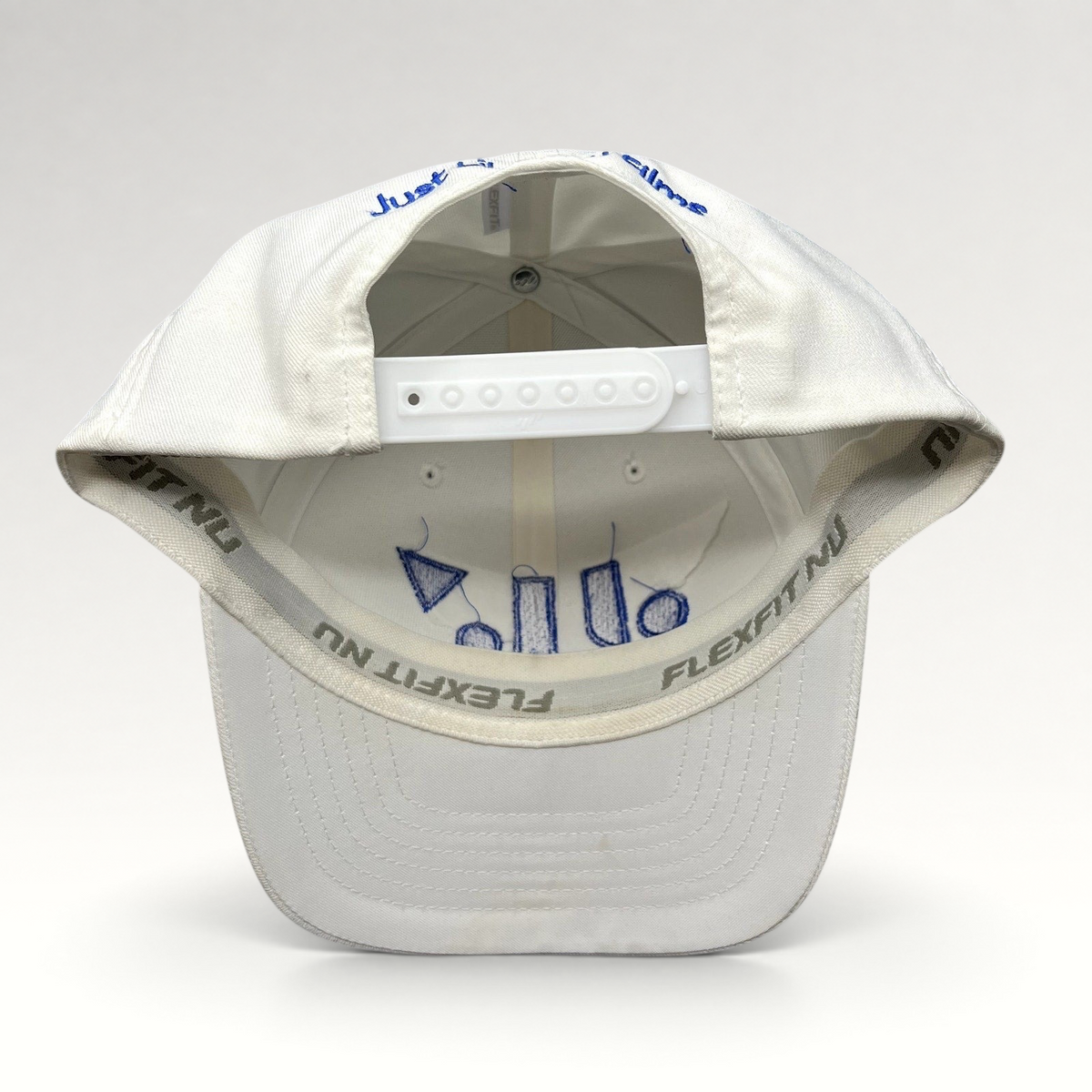 Raree Finds white Flexfit NU snapback hat showing interior royal blue embroidery and adjustable plastic strap