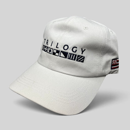 Raree Finds white cotton strapback cap with Trilogy branding and embroidered nautical signal flags on the front.