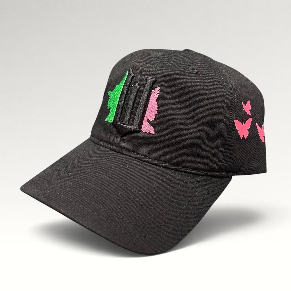 Raree Finds black cotton Wicked musical cap with green and pink embroidered character silhouettes and butterfly accents
