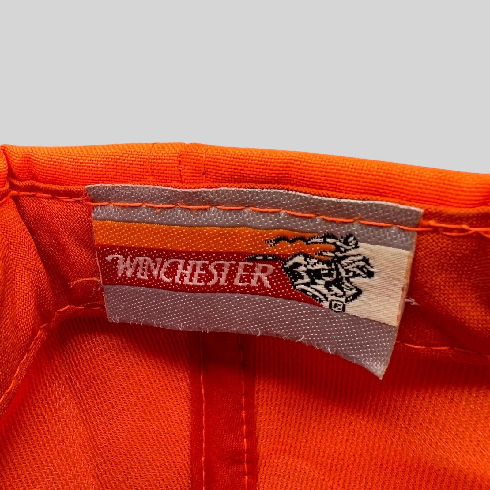 Raree Finds vintage Winchester hunting hat interior label with brand logo and deer graphic on blaze orange fabric