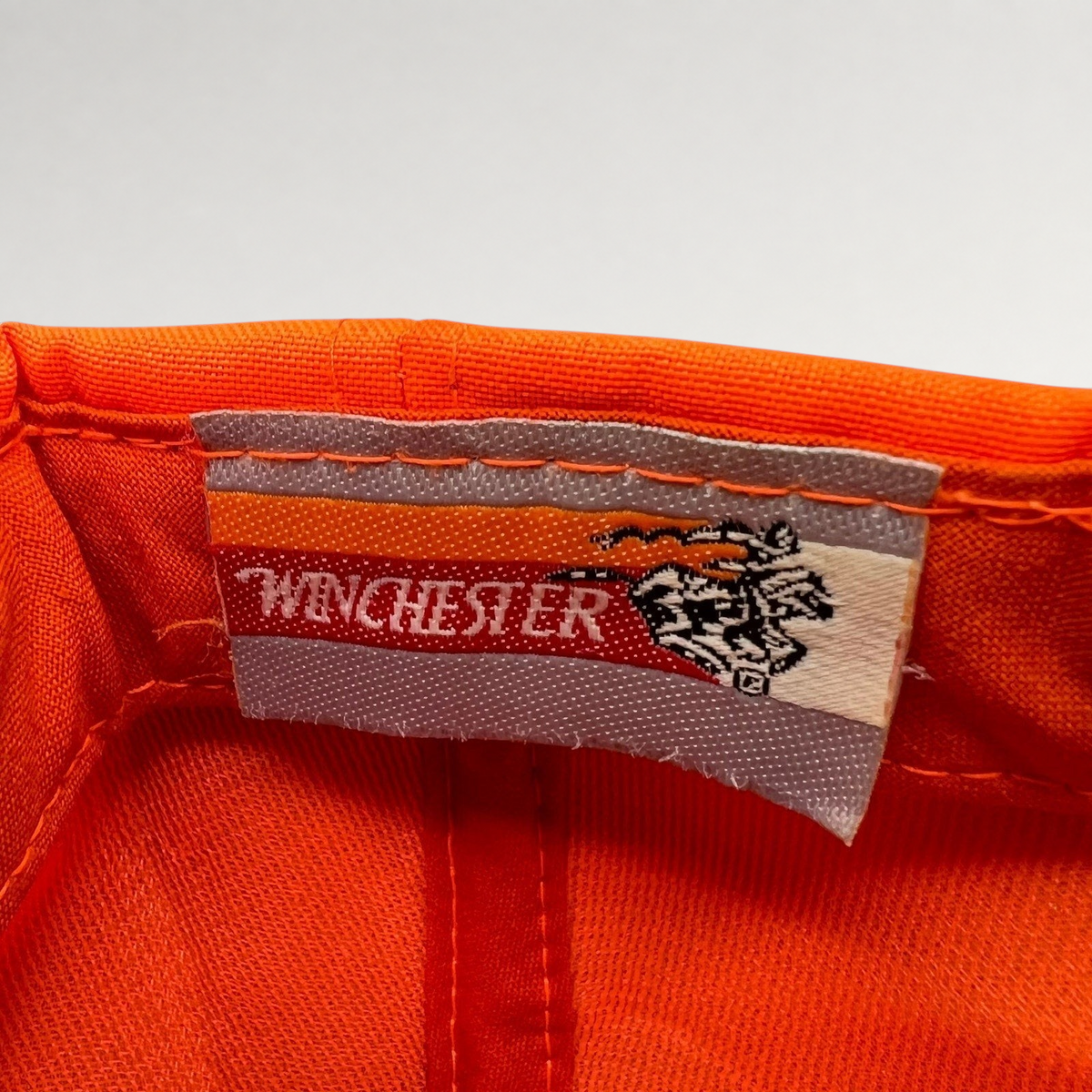 Raree Finds vintage Winchester hunting hat interior label with brand logo and deer graphic on blaze orange fabric