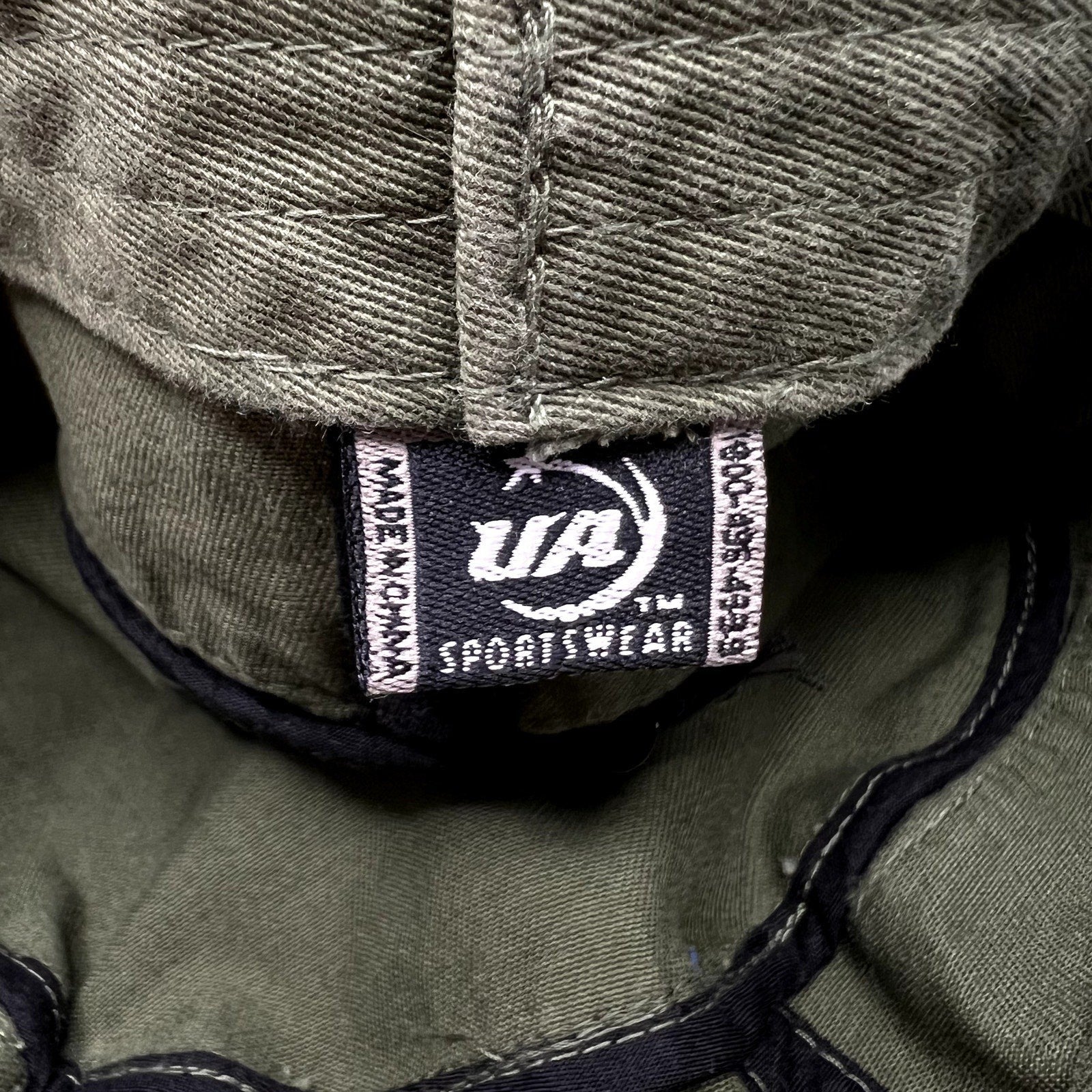 Raree Finds vintage X Games cadet cap interior tag showing UA Sportswear branding on olive green cotton fabric
