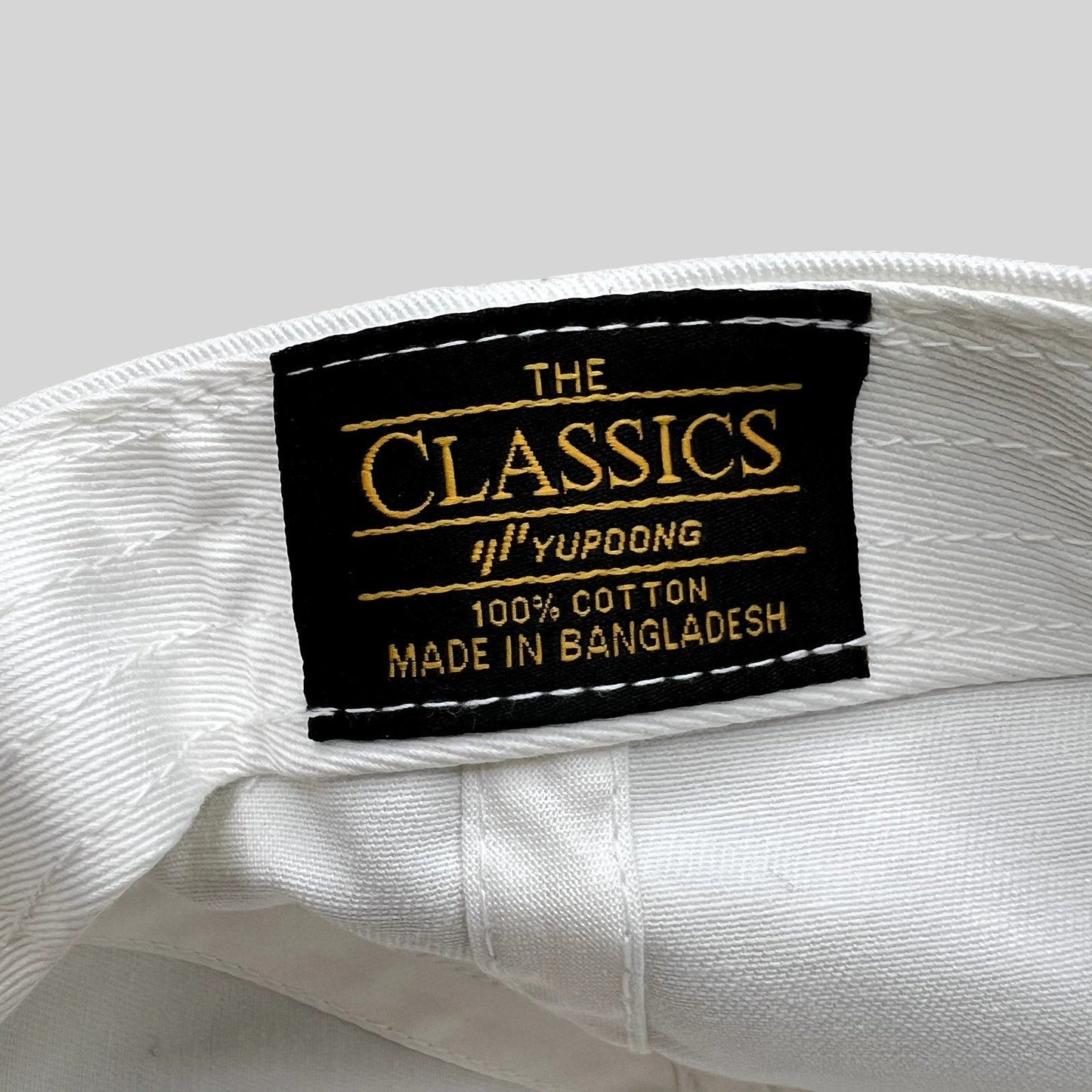 Raree Finds white cotton strapback hat interior featuring a black Yupoong Classics brand tag with gold embroidery