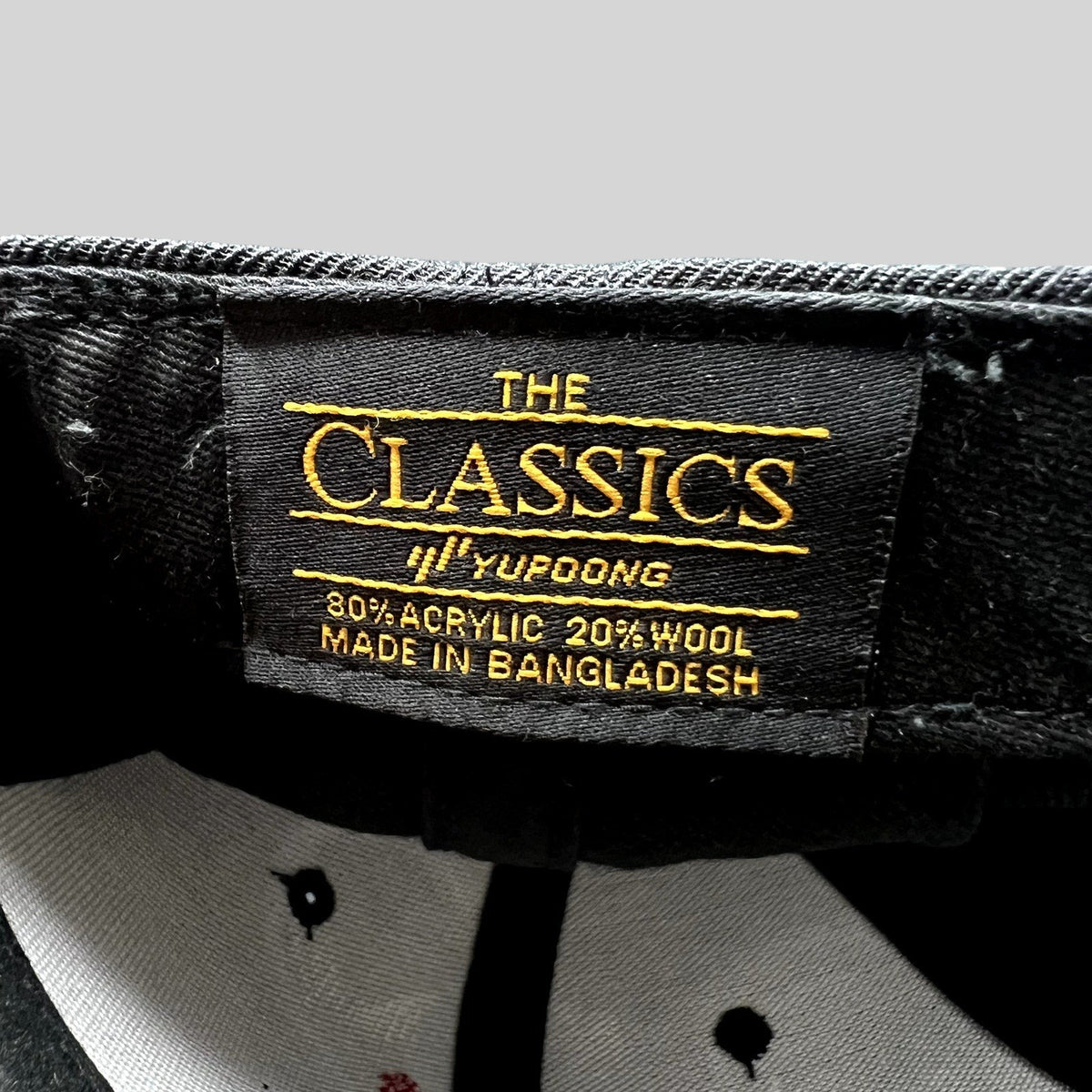 Raree Finds Yupoong The Classics black snapback hat interior label showing material composition and origin