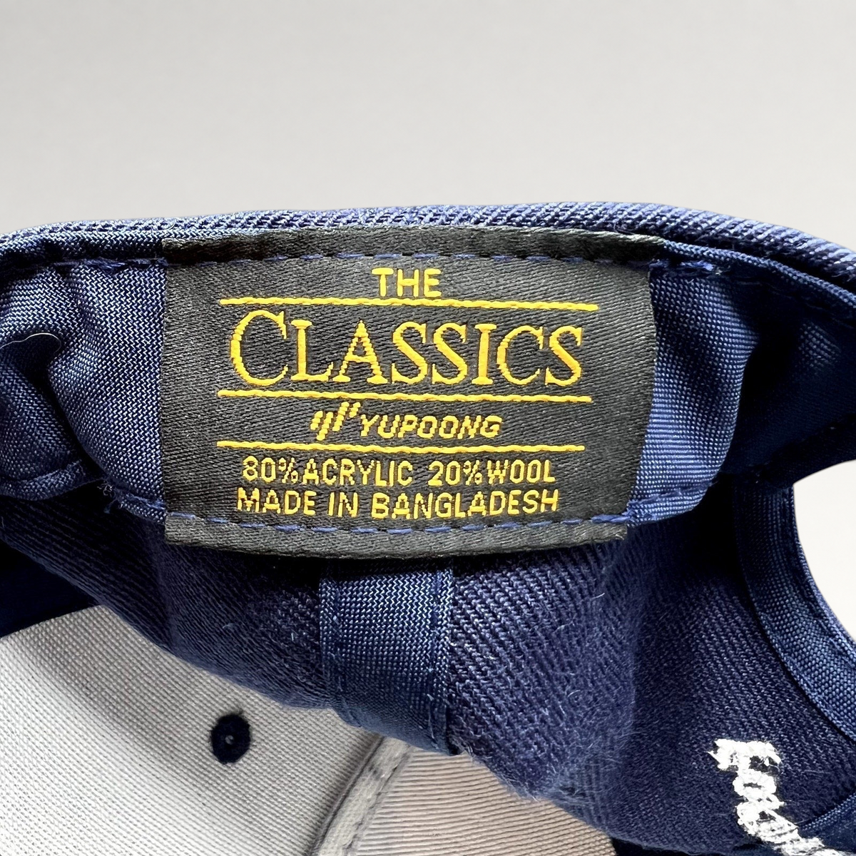 Raree Finds navy blue Yupoong Classics snapback hat interior label showing material composition and origin