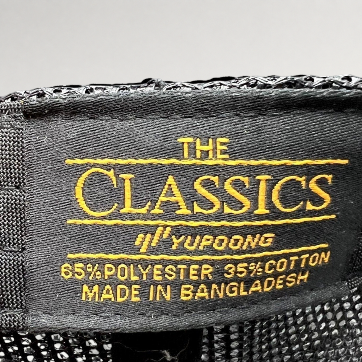 Raree Finds MOLLIE Aspen trucker hat interior tag showing Yupoong Classics branding and material composition