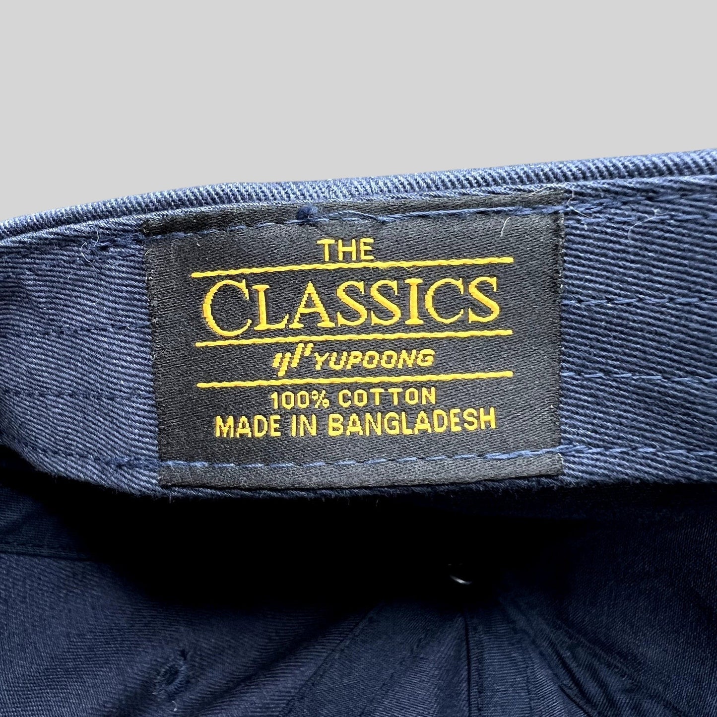 Raree Finds navy blue cotton dad hat interior label showing The Classics Yupoong branding and origin details
