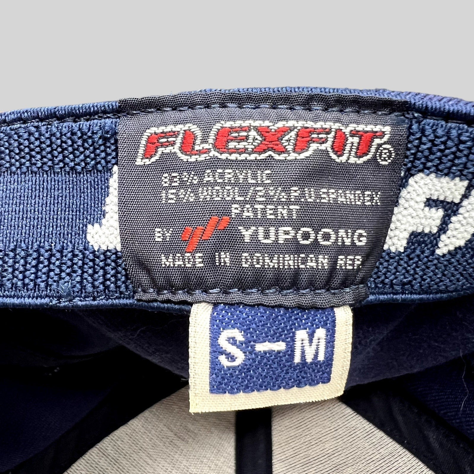 Raree Finds Yupoong Flexfit hat interior label showing size S/M and material composition on a navy blue cap